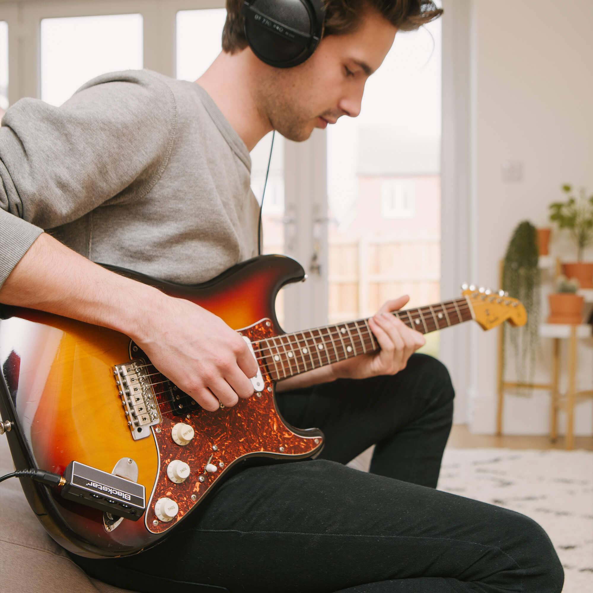 guitar player strumming guitar with Blackstar amPlug 2 FLY guitar amp plugged into guitar and headphones