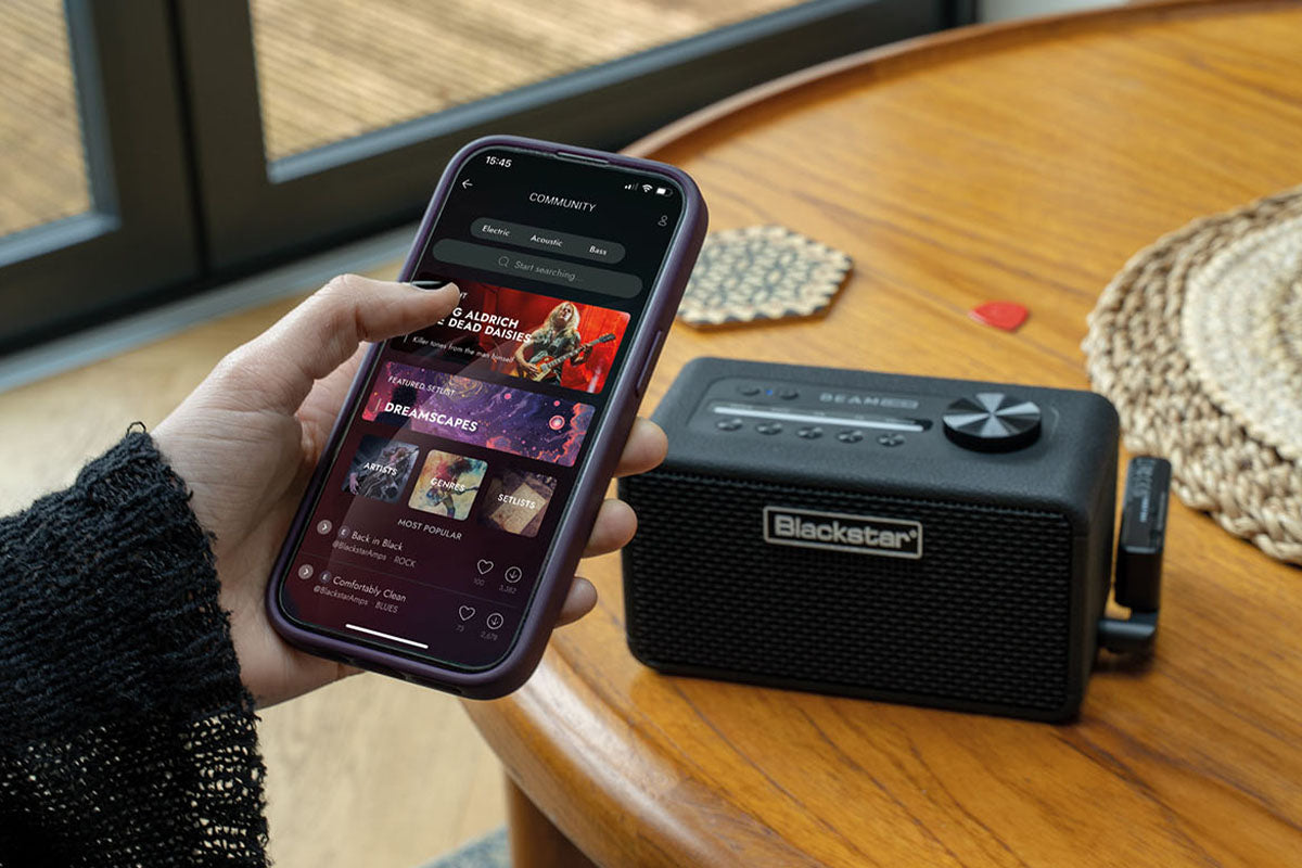Person using a smartphone with music app next to a BEAM Mini on a wooden table.