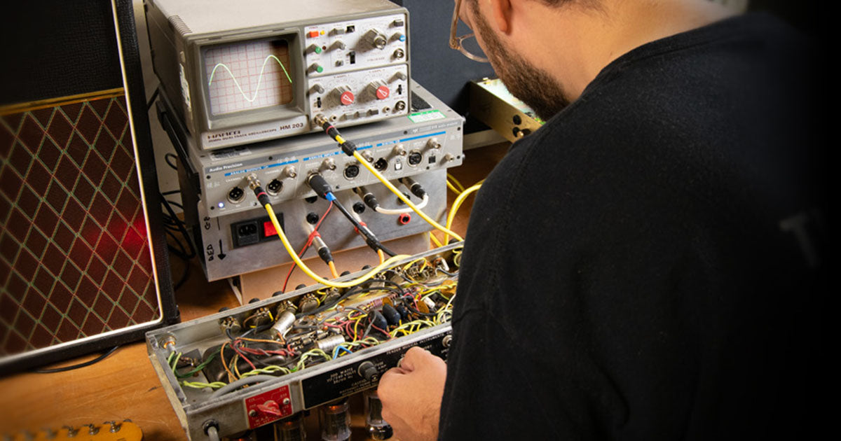 Ampton engineer working with the guts of classic amplifiers in a workshop setting
